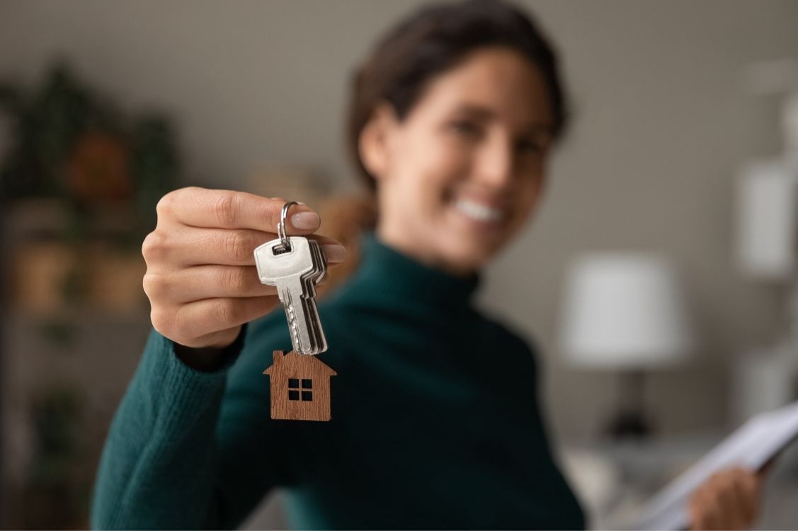 Smiling woman holding up the keys to a new home