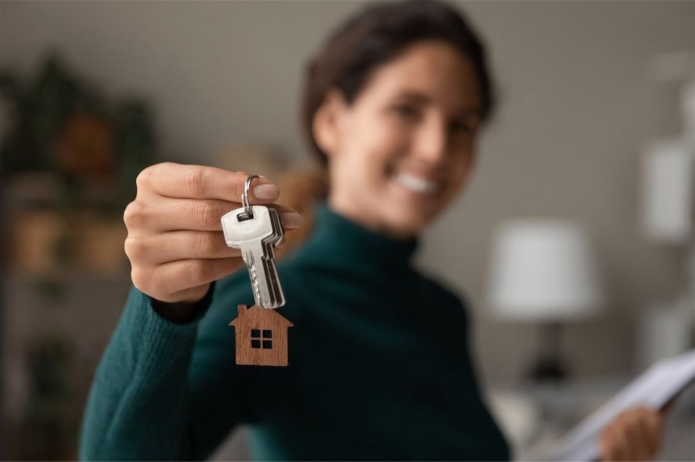 Smiling woman holding up the keys to a new home